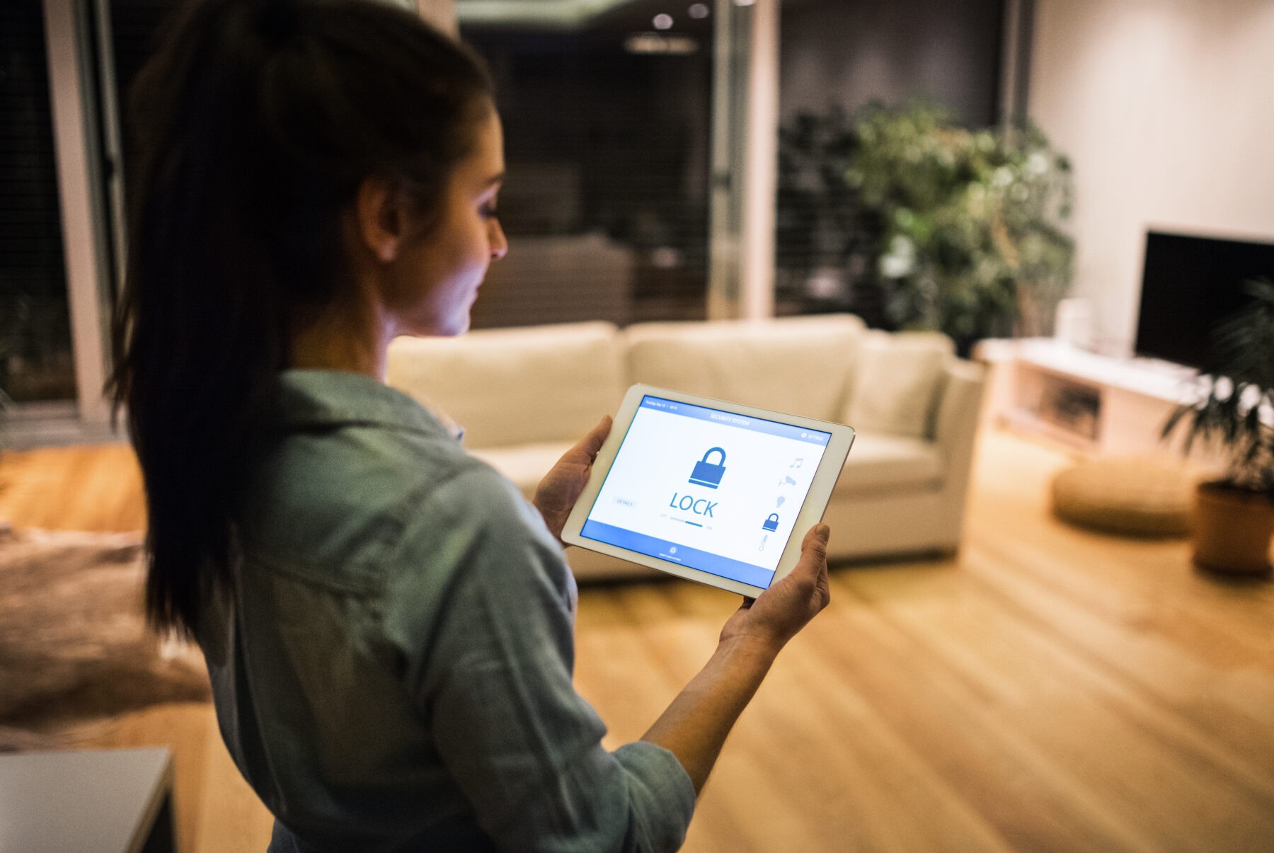 An unrecognizable woman holding a tablet with smart home control system.